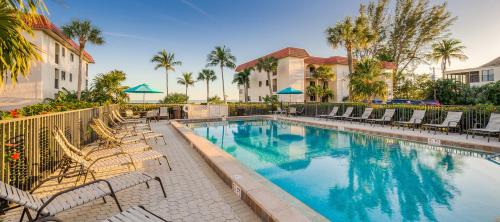 a swimming pool with chairs and palm trees at Island retreat with stunning gulf views Sanibel Island 3A2 in Sanibel