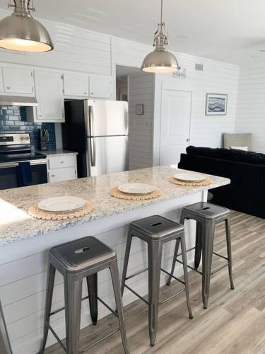 a kitchen with a counter with three stools around it at Coastal Condos on the Marsh 6B in Dauphin Island