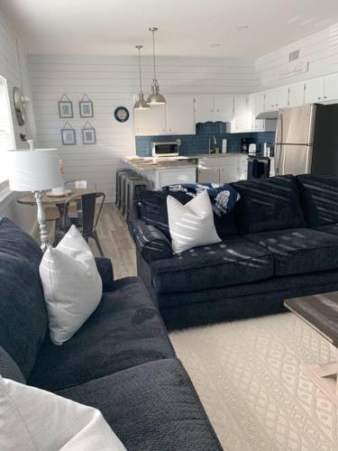 a living room with a black couch and a kitchen at Coastal Condos on the Marsh 6B in Dauphin Island