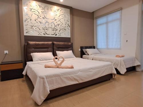 two beds in a room with two towels on them at W&P Lakeside Homestay Sri Gading in Sri Gading