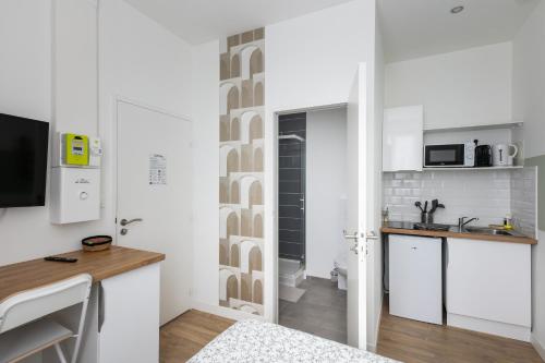 Elle comprend une petite cuisine avec des placards blancs et un bureau. dans l'établissement Le Vigilant, à Brest