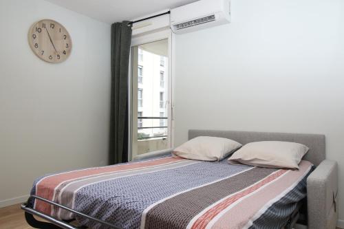 - une chambre dotée d'un lit avec une horloge murale dans l'établissement Le Mistral - Calme et Climatisé - Hypercentre - Terrasse - Wifi, à Avignon