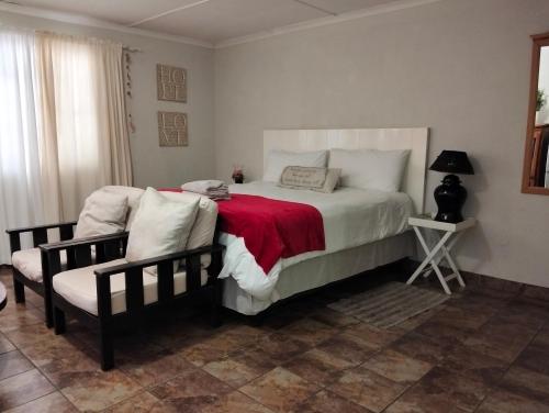 a bedroom with a bed with a red blanket and a chair at Jozini Lebombo Lodge in Jozini