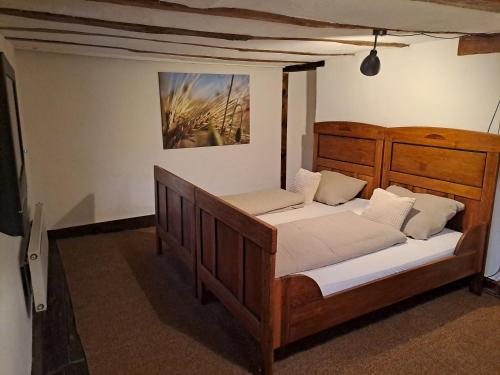 a bedroom with a wooden bed with white sheets at Haus Burg, Ferienhaus in Bongard