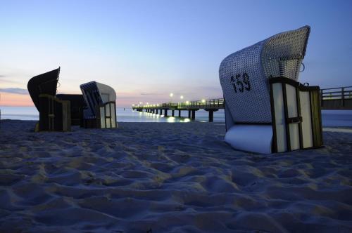 a group of chairs on a beach with a pier at "NordWest" Ferienwohnung in Prerow