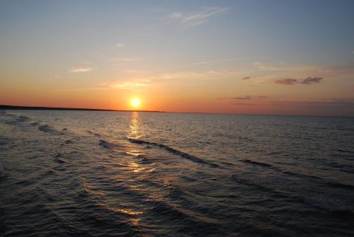 a sunset over the ocean with a boat at "NordWest" Ferienwohnung in Prerow