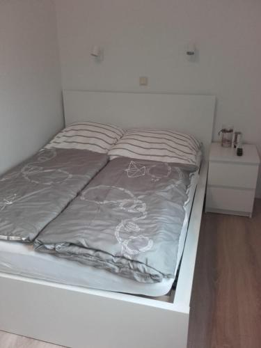 a white bed with gray sheets on top of it at "Heimathafen" mit Sauna in Hohenkirchen