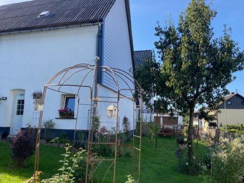 a greenhouse in a garden next to a white house at Ferienwohnung "Wiesensee" im historischen Landhaus in Pottum