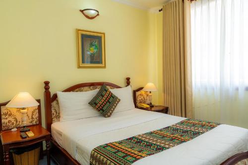 a bedroom with a bed and two lamps and a window at Hoang Ha Boutique Hotel in Ho Chi Minh City