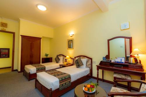 a hotel room with two beds and a desk at Hoang Ha Boutique Hotel in Ho Chi Minh City