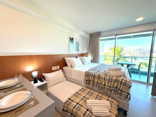 a bedroom with a bed and a table with plates on it at RN Studio Premium Max Rev in Maceió