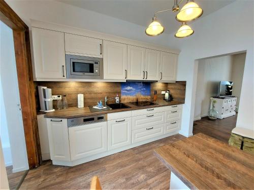 a kitchen with white cabinets and a sink and a microwave at Komfortfewo Meeresleuchten in Sassnitz