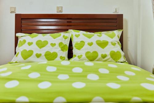 a green bed with white pillows and a green comforter at MH - Upper Floor Apart in Douala