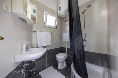 a bathroom with a sink and a toilet and a shower at Apartman Štorija in Brela