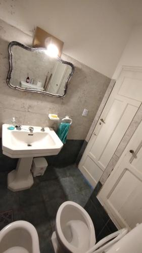 een badkamer met een wastafel, een toilet en een spiegel bij Gen Viajero Hostel in Merlo