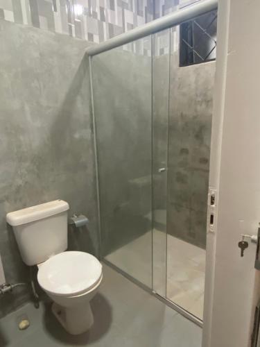a bathroom with a toilet and a glass shower at Apartamento térreo próximo ao Iguatemi in Torto