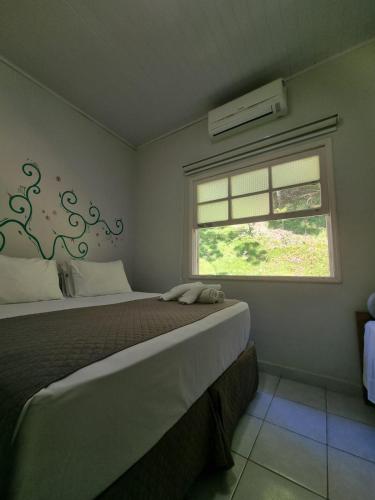 a bedroom with a large bed and a window at Recanto das Carpas in Ilhabela