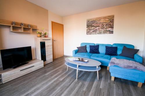メッペンにあるFamilienhof Brüning - Ferienwohnung Hofblickの青いソファとテーブルのあるリビングルーム