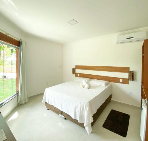 a white bedroom with a large bed with white sheets at Corumbau Recanto dos Pássaros in Corumbau