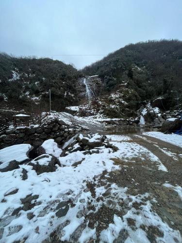 a snow covered mountain with a waterfall in the background at AĞARAN Wooden Houses 2 in Cayeli