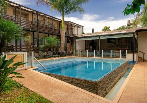 a swimming pool in front of a building at INGA by DOT Suites in Puerto Iguazú