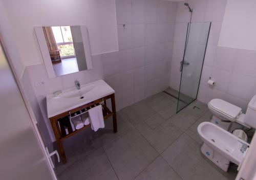 a white bathroom with a sink and a toilet at INGA by DOT Suites in Puerto Iguazú