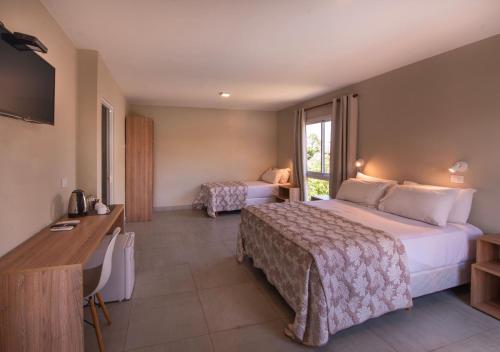a hotel room with two beds and a desk at INGA by DOT Suites in Puerto Iguazú