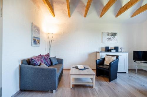 a living room with a couch and a chair at Ferienwohnung Ebbe mit Loggia und schönem Ausblick am Badesee Tannenhausen in Aurich