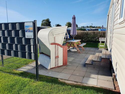 a fence with a chair and an umbrella on a patio at Campingland Ostsee - Mobilheim 155Meerluft in Schashagen