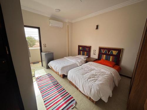 a bedroom with two beds and a rug on the floor at wawat in Abu Simbel