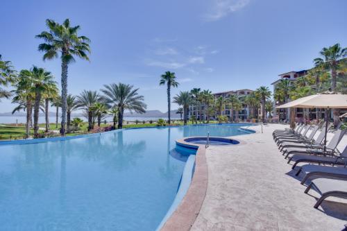 a large swimming pool with chairs and palm trees at Colorful Paraiso del Mar Resort Condo with Patio! in La Paz