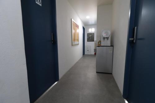 a hallway with a blue door and a refrigerator at HAH Guesthouse in Seoul