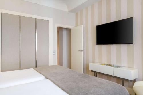 a bedroom with a bed and a tv on a wall at NH Collection Madrid Colón in Madrid