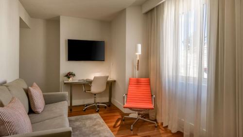 a living room with a couch and a desk with a computer at NH Collection Madrid Colón in Madrid