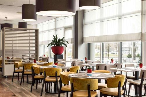 a restaurant with tables and chairs and windows at NH Maastricht in Maastricht
