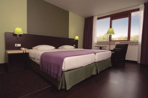 a hotel room with a large bed and a window at NH Maastricht in Maastricht