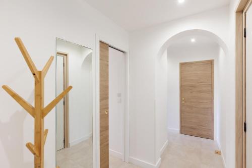 un couloir avec des murs blancs et une porte en bois dans l'établissement Appartement 4 personnes situé à 2 pas de la Croisette et des plages, à Cannes
