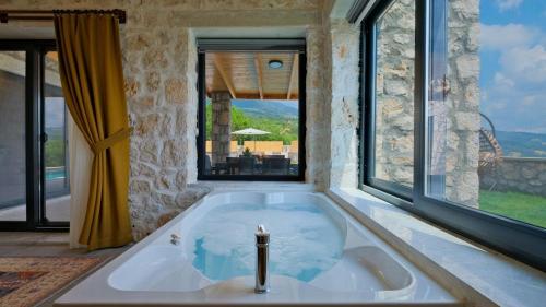 a bath tub in a room with a large window at Villa TEPE in Arsaköy