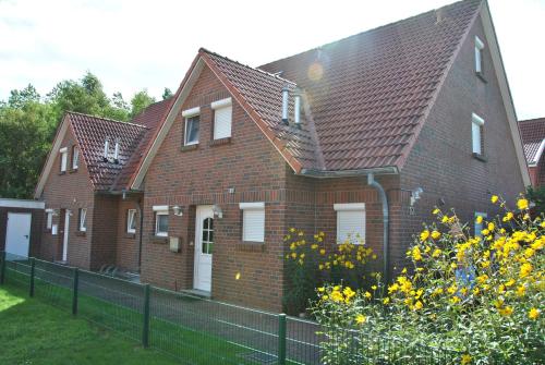 a brown brick house with white windows and a fence at Ferienhaus Harlebogen in Wittmund