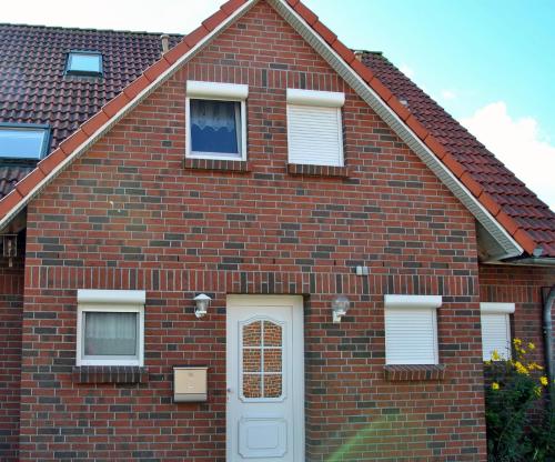 a red brick house with a white door at Ferienhaus Harlebogen in Wittmund