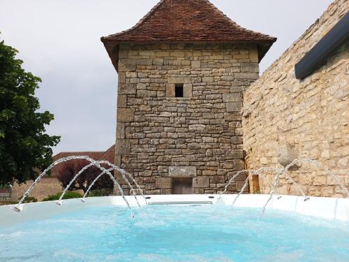 une fontaine devant un bâtiment en pierre dans l'établissement La Maison Haute, à Nailhac