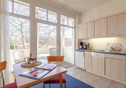 eine Küche mit einem Tisch und einigen Stühlen und Fenstern in der Unterkunft Studio Ostseewind Residenz Seeblick in Ostseebad Sellin