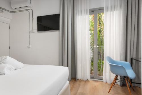 a white bedroom with a bed and a blue chair at Brondo Architect Hotel in Palma de Mallorca