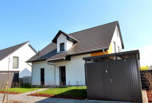 een wit huis met een zwarte garage bij Villa Aquila Luxus-Maisonette Ferienträume Dachterrasse in Göhren-Lebbin