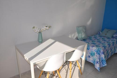 a white table with two chairs and a vase with flowers at Incatevole sul mare in Belmonte Calabro