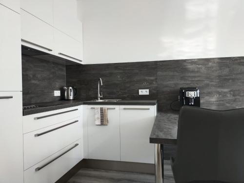 a kitchen with white cabinets and a sink at Apartmány Elite - Frištenského in Olomouc