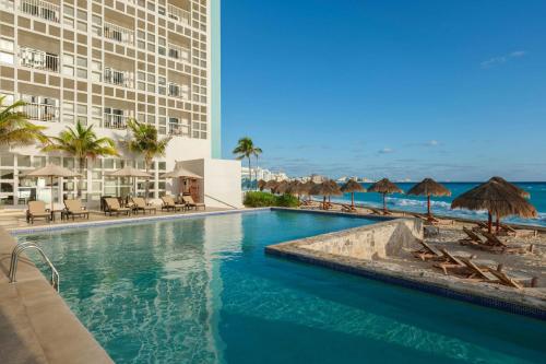 a pool at a resort with chairs and umbrellas at The Westin Resort & Spa Cancun in Cancún
