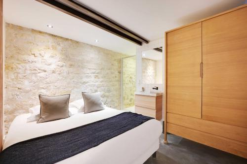 une chambre avec un grand lit et un mur en pierre dans l'établissement Charming apartment - 1BR- 4P- Arts et métiers, à Paris