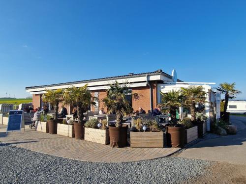 a restaurant with potted plants in front of a building at Ostseeferienpark Walkyrien - Bootsmann 08 in Schashagen
