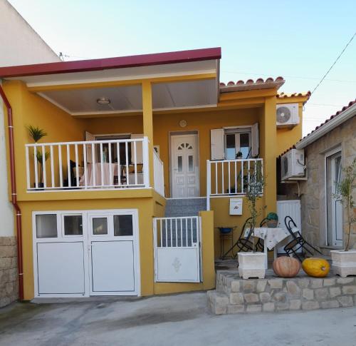 a yellow house with a porch and a balcony at Paraíso da Foz do Sabor in Torre de Moncorvo